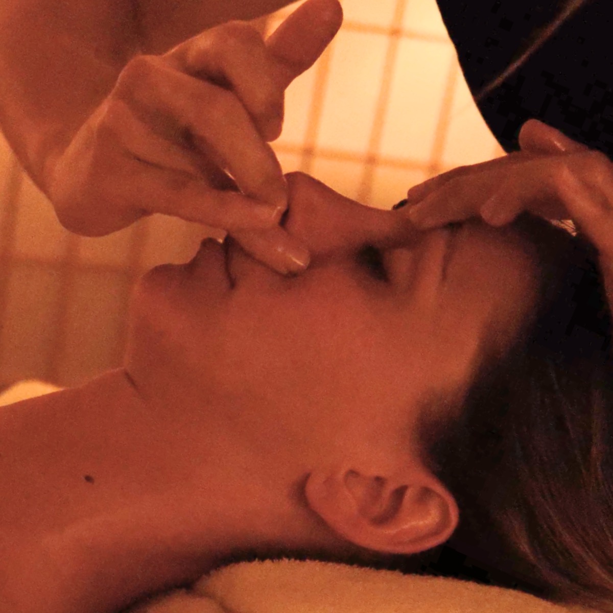 Close-up of fingers applying gentle acupressure near the upper lip during a Visaj session