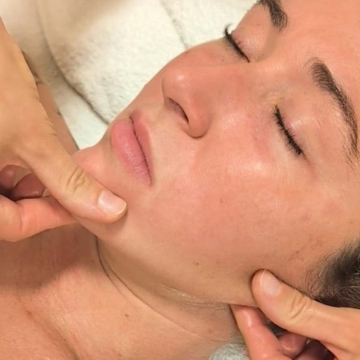 Hands performing a facial massage along the jawline during a Visaj session in Noosa