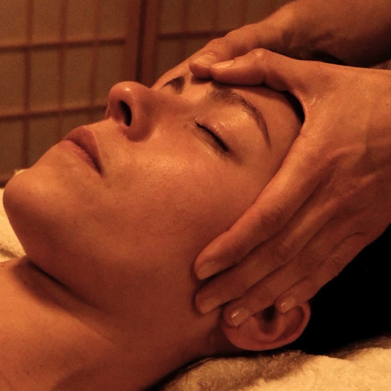 Close-up of a facial massage, hands working around the temple and ear