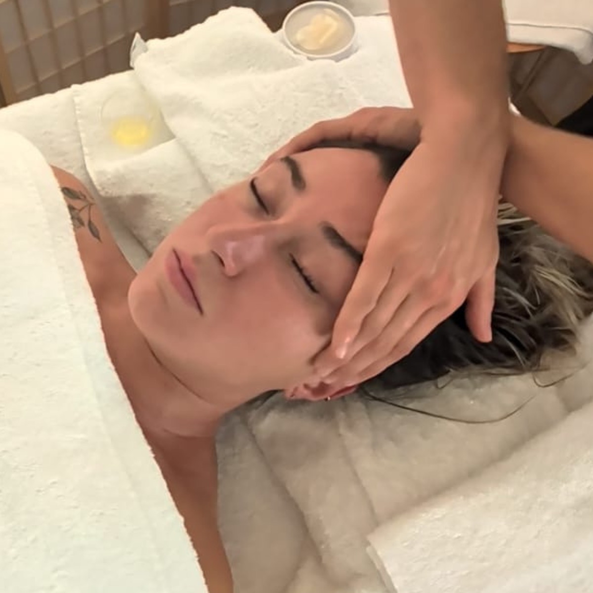 Close-up of a facial lymphatic drainage massage session, hands working gently around the forehead and temple