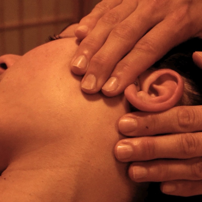 Hands performing a gentle facial lymphatic drainage massage on the neck and collarbone